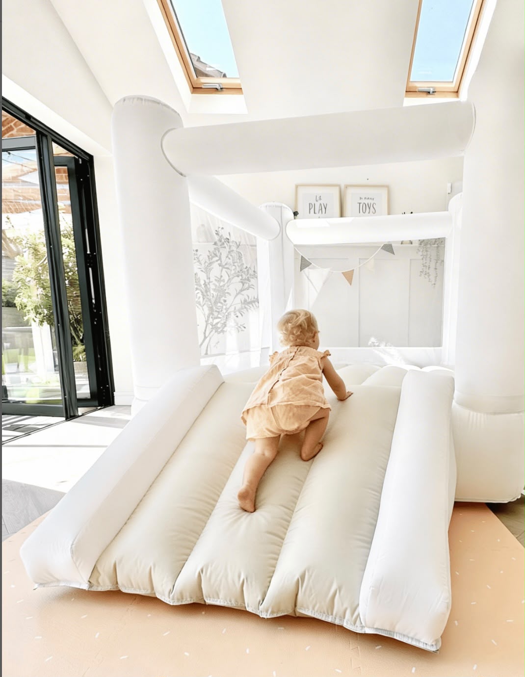 Toddler climbing a white inflatable soft play castle with slide