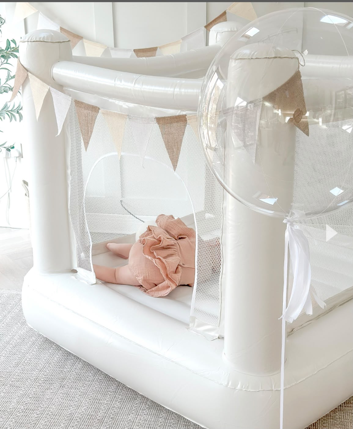 Baby playing inside a white inflatable bouncy castle with bunting
